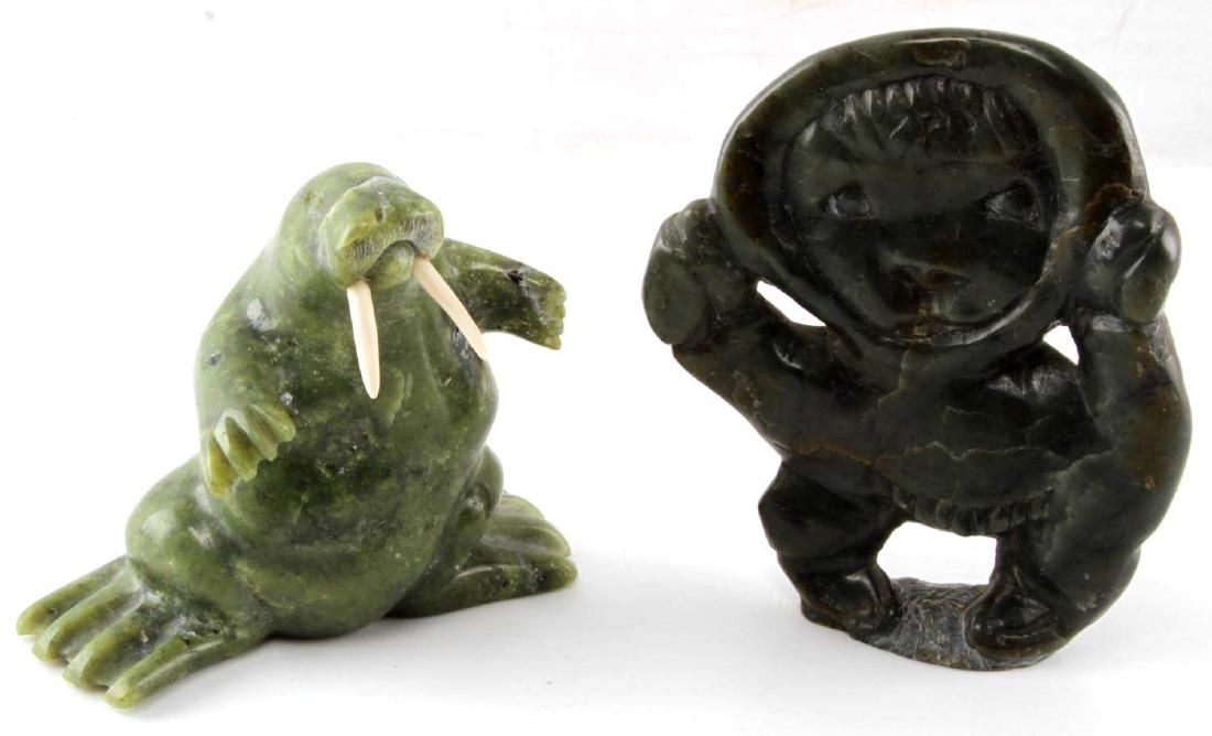 2 INUIT SOAPSTONE CARVED SCULPTURES WALRUS: Green and grey soapstone with bone tusks. Walrus measures 4 X 4.5 inches with sticker to bottom. Other figure seems human-like, measures 5.25 inches tall and 1 inch wide, signed and Canada sticker to 