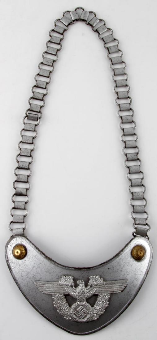 WWII GERMAN THIRD REICH POLICE GORGET: This is a German WWII Police gorget with Reichsadler, wreath, and swastika. Maker marked 'A' for Assman on reverse. Has a green wool backing, chain, and uniform hooks. Gorget measures 6.5 inches wide.