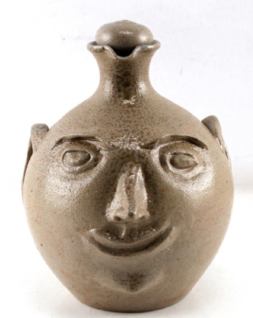 VERNON OWENS JUGTOWN POTTERY FACE JUG W STOPPER: In very good condition with original stopper and signed on bottom. Measurements are 11 inches in height with a 9 inch diameter.