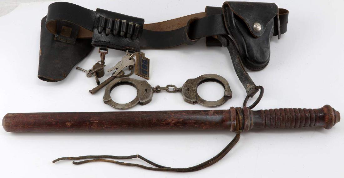 BRITISH POLICE BELT BATON & ACCOUTREMENTS LOT: This lot includes 1 vintage police belt with a variety of accoutrements including .38 S&W pistol ammunition, a police baton, keys, "The Acme Thunderer" whistle, handcuffs, a holster, and more. Belt is