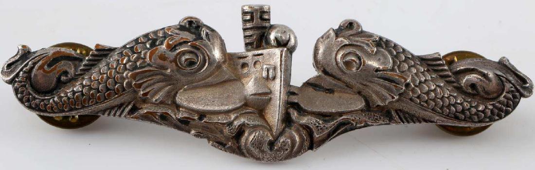WWII US NAVY SUBMARINE WARFARE DOLPHIN EM BADGE: Silver-colored dolphin badge of an enlisted US Navy submariner from WWII. Dual-pin back. The silver coloration is worn away on the front of some portions of the badge revealing a bronze color undernea