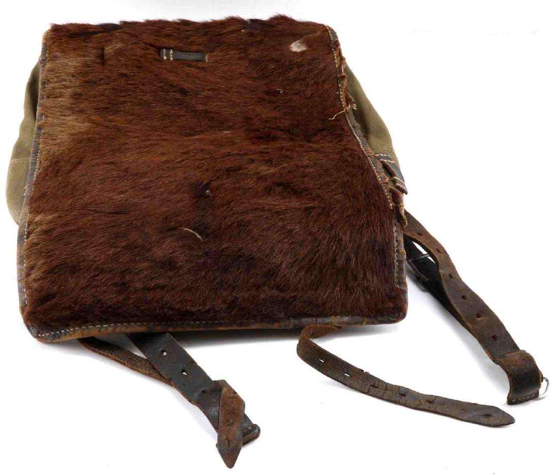 WWII GERMAN THIRD REICH PONY FUR BACK PACK: A Moritz Stecher Freiberg Tornister 34 Back Pack in green canvas and fur. Straps are stamped 1940 and 1943. Good condition overall with moderate staining, color loss, and fur loss present. Roughly 12"