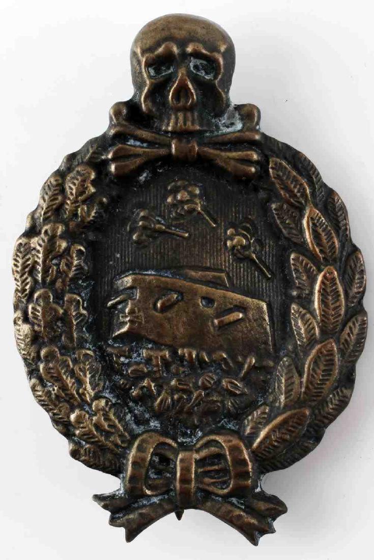 IMPERIAL GERMAN WWI ARMORED TANK ASSAULT BADGE: Imperial German WWI armored tank assault badge. Measures 1 11/16 inches wide by 2 9/16 inches tall. The front shows a tank in the center of a 'no mans land' trench. There is a skull and cross bones at