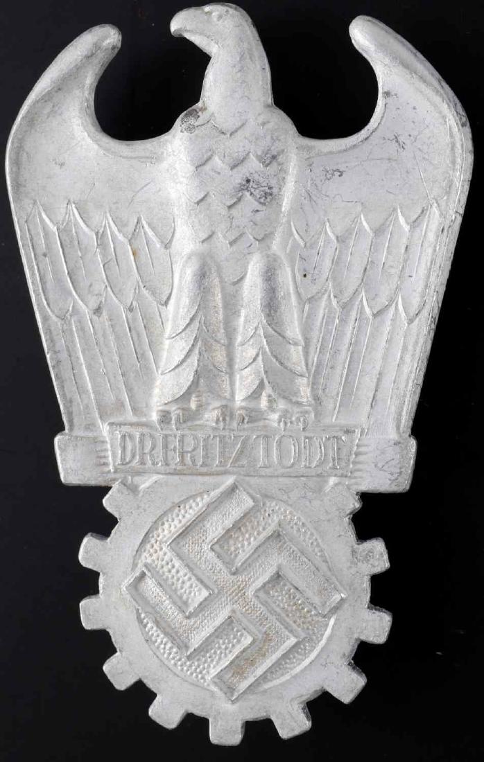 WWII GERMAN THIRD REICH TODT ORGANIZATION BADGE: Todt Organization badge decoration. Featres seated Reichsadler on a cogged swastika with 'Dr. Fritz Todt' written between them. Wide vertical brass pin back. Aluminum construction. Unauthenticated/Sol