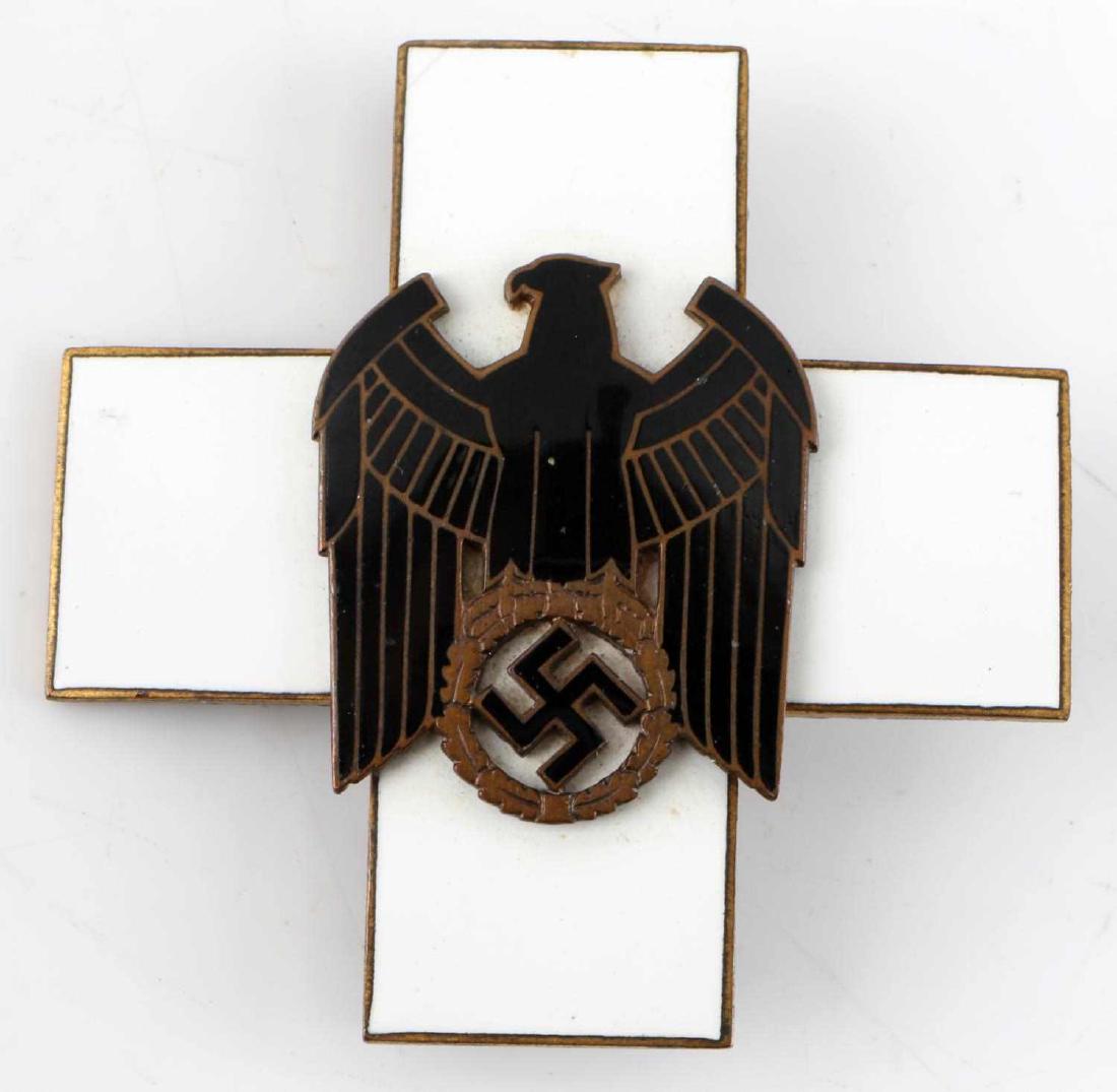 THIRD REICH GERMAN ENAMELED WELFARE CROSS BADGE: Brass badge with enamel to front and eagle affixed to cross. Measures 2.25 X 2.25 inches. No maker's mark.