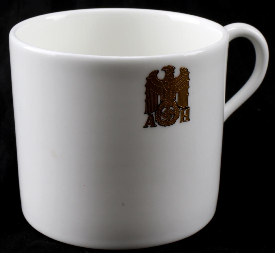 GERMAN THIRD REICH HITLER PORCELAIN ALLACH CUP: Small porcelain cup with the formal gold 'AH' Reichsadler mark of Hitler. Has Allach maker mark on the bottom. Brought to the US by a member of the 506th PIR. In very good condition. CSG 45