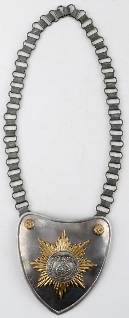 GERMAN WWII SA FLAG BEARER GORGET WITH CHAIN: Aluminum construction with starburst design with eagle and swastika. metal chain. RZM M34/? marked. Shield measures 5.5 X 5 inches. Chain measures 25 inches long. Unauthenticated, sold as is. This ite