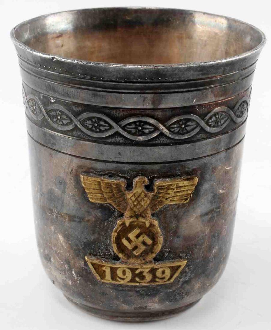 GERMAN WWII ARMY PRESENTATION WINE CUP CHRISTOFLE: Silver plate cup with engraved border and 1939 eagle with swastika affixed to front. Bottom is maker marked 'Christofle' with 1940 below and OC symbol with scales above. Measures 3 inches tall and 2 5