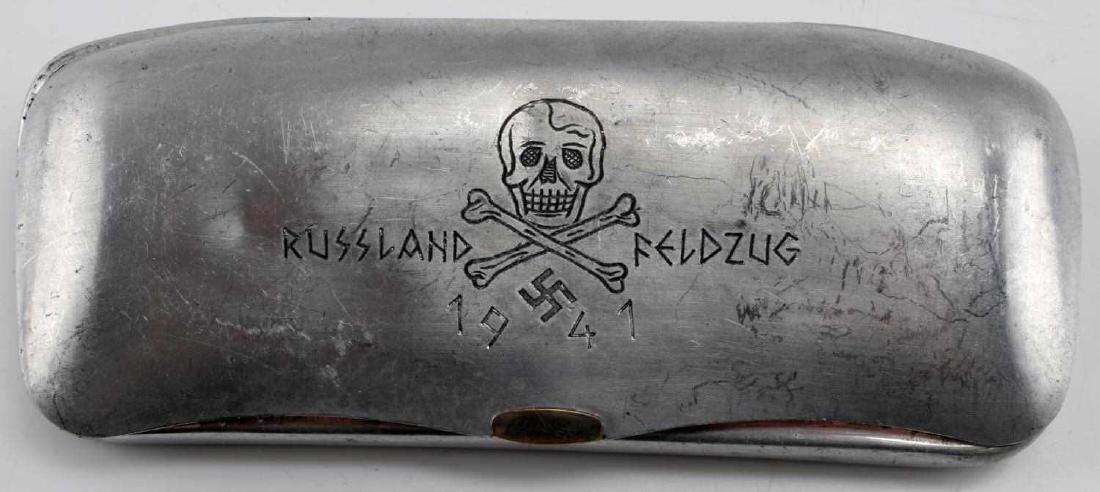 WWII GERMAN 3RD REICH RUSSIAN FRONT EYEGLASS CASE: Aluminum eyeglass case with a skull and crossbones above a swastika with 'Russland Feldzug 1941' written around it. In very good condition. This item has a reserve.
