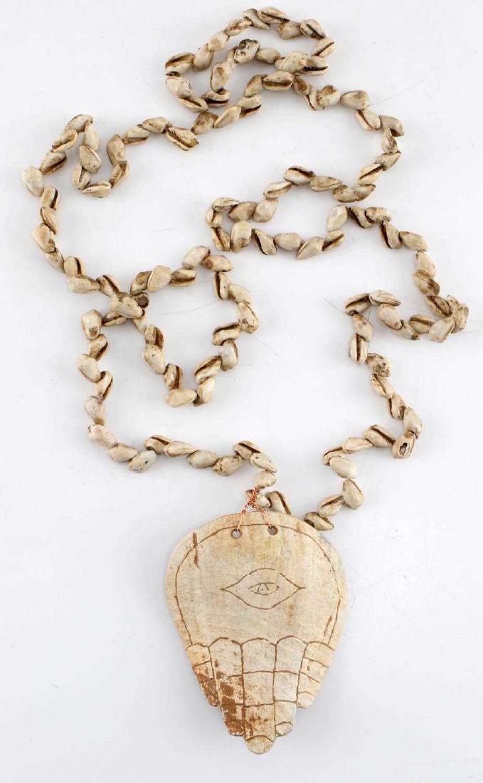 ANTIQUE WORKED SEA SHELL BONE HAMSA & EYE NECKLACE: Antique Worked Sea Shell Bone Hamsa & Eye Necklace with string of sea shell beads along the necklade while the central pendant appears to be a primitive rendition of a HAMSA hand - symbol with a centr