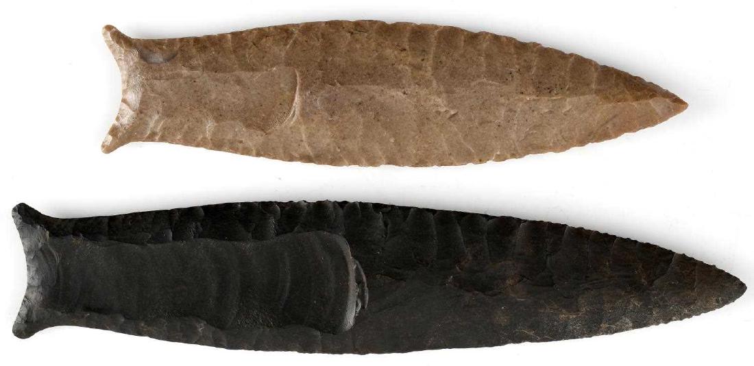 2 CUMBERLAND ARROWHEAD POINTS W 6 INCH 4 INCH: One black with flute to each side, excellent parallel flaking, flared ears and ground base, 6.25 inches. The other is tan, somewhat shiny, excellent flaking and ground base, 4.75 inches. Very good con