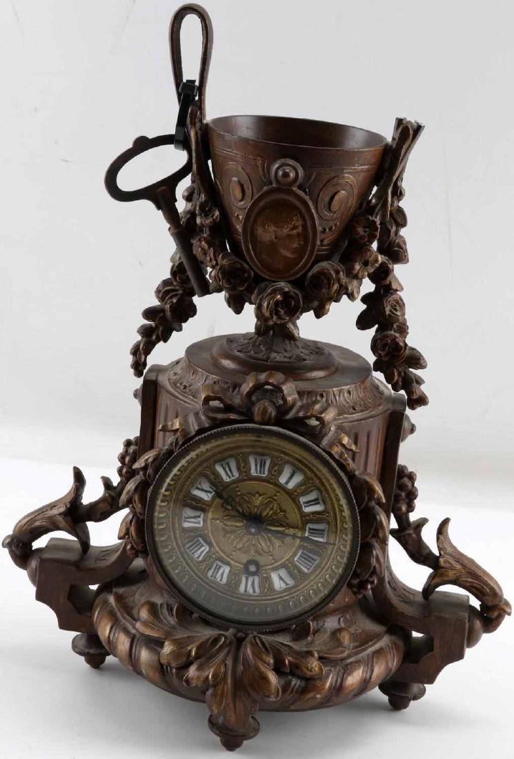 19TH C FRENCH WORKING PAINTED SPELTER MANTLE CLOCK: 19th century French painted spelter working mantle clock. Has key. Clock face is brass and has glass covering. Clock has floral garland design throughout with chalice at the top. Classical portrait at