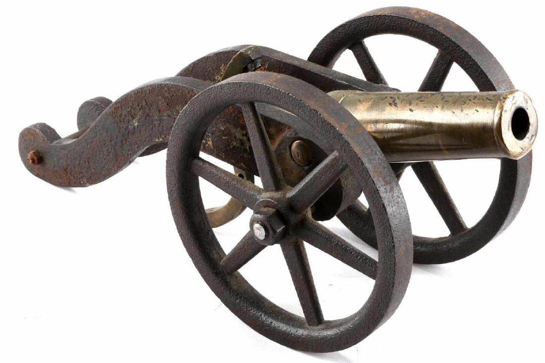19TH CENTURY BRASS PERCUSSION CAP SIGNAL CANNON: 19th Century signal cannon with a percussion cap firing mechanism. Cannon and hammer are brass and the carriage and wheels are iron. Measures 18 inches in length overall. The top of the cannon shows s