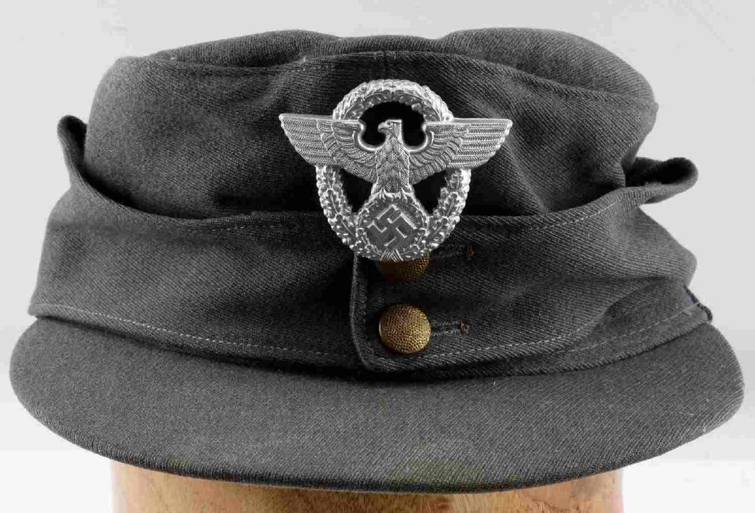 WWII GERMAN THIRD REICH M 43 POLICE CAP: German wool M43 police cap. Marked "Gegr. 1902," "Marie Flauna & John," and size "55 1/2" on interior. Very good overall with intact though somewhat damaged leather sweatband and highly frosted alumin
