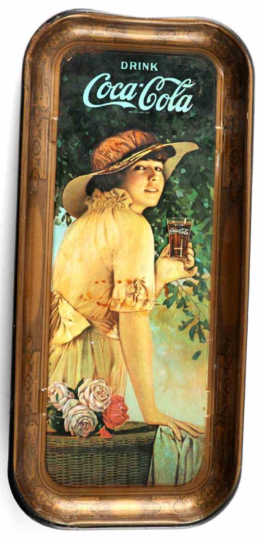 COCA COLA RETRO TIN TRAY W WOMAN HOLDING DRINK: Retro Coca-Cola tin tray showing a vintage styled woman holding a glass of Coke. In good condition with some scratches and slight stains. Measures 18.5 inches by 8.5 inches.