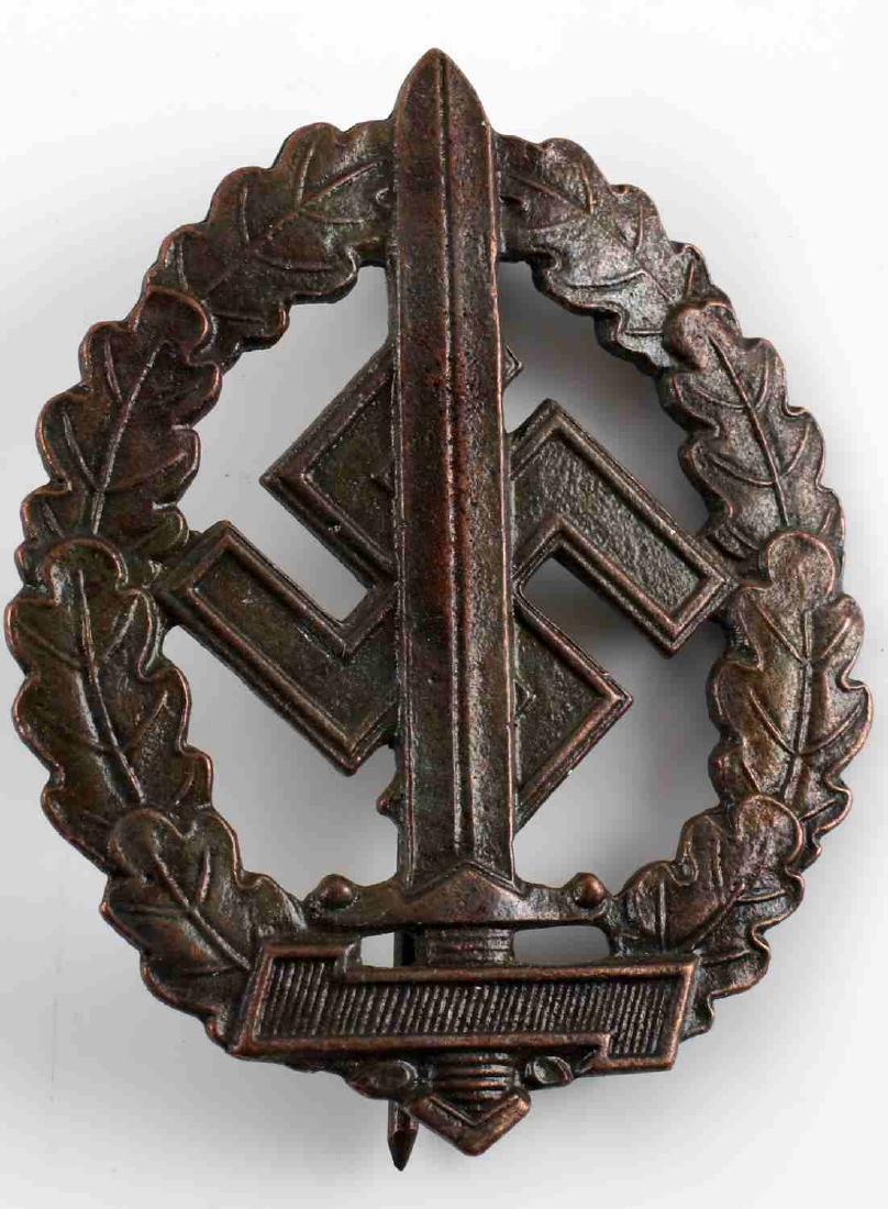 WWII GERMAN 3RD REICH SA WAR WOUNDED SPORTS BADGE: German SA War Wounded Sports Badge in bronze. Sword in center with swastika background surrounded by oak leaf wreath. The reverse is maker marked "RZM M1/100. Thin vertical back pin. Bronze constructi