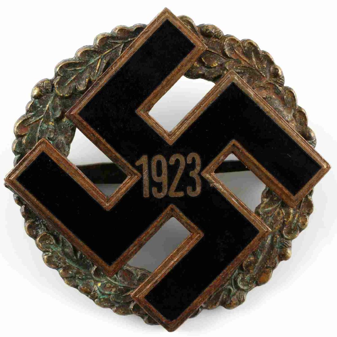 WWII GERMAN GAU ALLEGEMEINE ENAMELED BADGE: German Gau Allegemeine badge. Black enameled swastika over a heavy patina bronze oak wreath with the year 1923. Horizontal pin back. Very good overall.