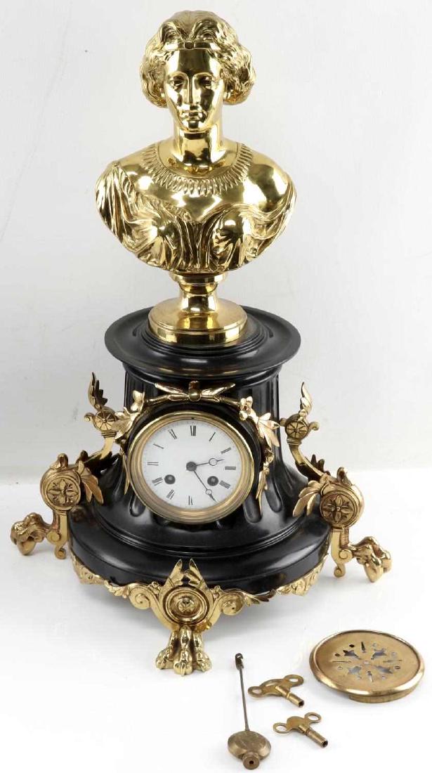 19TH CENTURY FRENCH ORNATE CLOCK W GOLD BUST: Ornate 19th century French clock. Has gold tone bust at top. Base is black with gold tone legs and floriated decoration. Clock face is white enamel with two holes for winding. Measures 20.75 inches ta