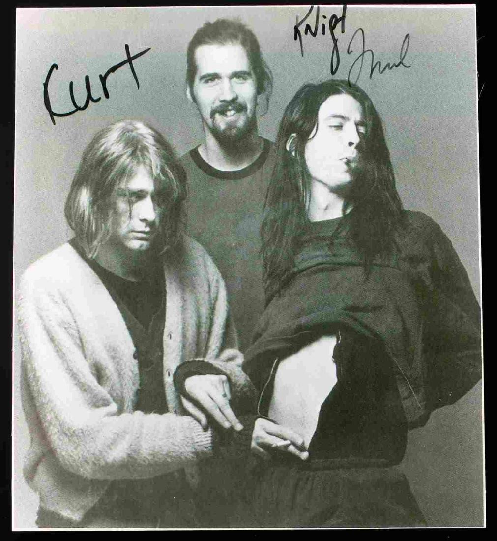 PHOTOGRAPH AUTOGRAPHED BY ALL MEMBERS OF NIRVANA: Black and white and photograph of Nirvana. Autographed by all three members. Signatures from left to right over band member's heads - "Kurt" (Kurt Cobain) "Krist" (Krist Novoselic) and "Grohl" Dave Gr