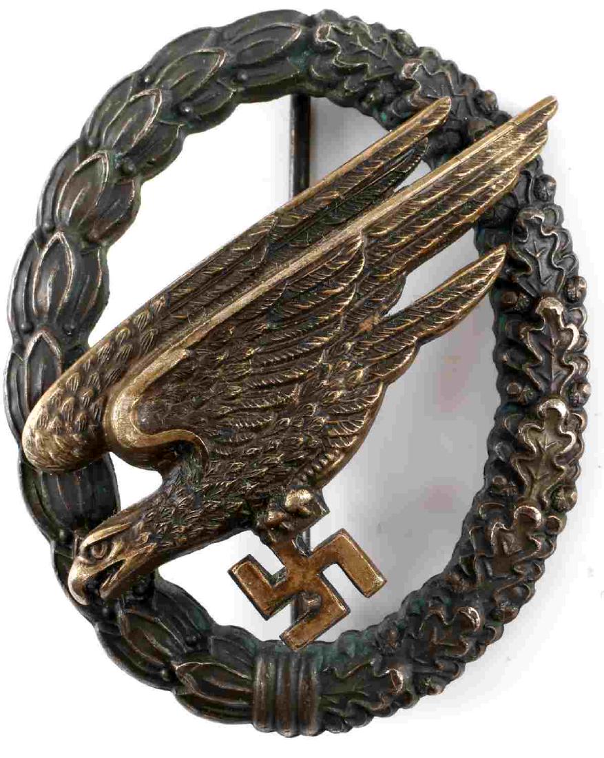 WWII GERMAN LUFTWAFFE PARATROOPER BADGE: German Luftwaffe Fallschirmjager badge. Dull gold diving eagle/swastika on an open darkened oak/laurel wreath. 2 piece domed rivet construction with thin vertical pin back. Reverse marked "G.H.Osang D