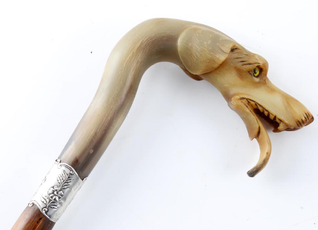 ANTIQUE HORN HOUND HEAD SWORD CANE SILVER COLLAR: Sword cane with a hounds-head grip made out of horn. The collar of the cane is silver. Blade measures 27 1/2 inches in length and has a blued-and-gilt design on it. Measures 35 inches in length overal