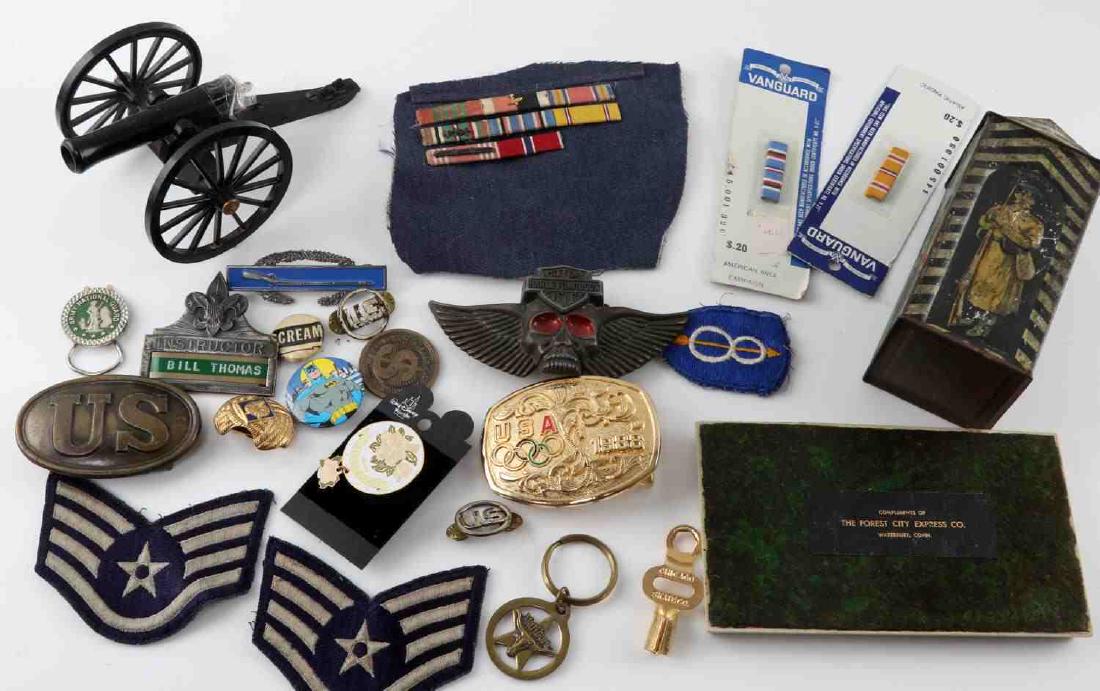LOT OF US MILITARY INSIGNIA AND COLLECTIBLES: Some items included are: plastic cannon on base, Harley Davidson buckle, US belt buckle, tin container, patch, ribbon rank bars and more. Condition varies.