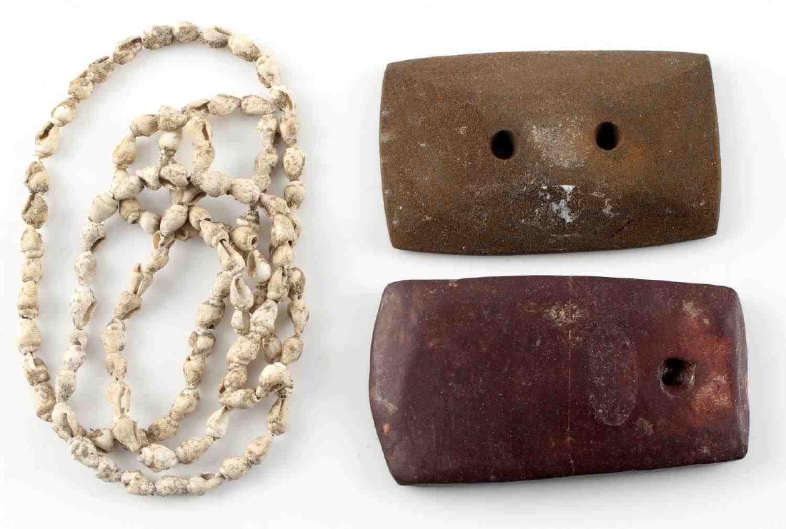 LOT TWO NATIVE AMERICAN GORGETS & SHELL NECKLACE: Woodland red stone one-holed gorget from Kent County, Ohio. Has scratch around middle and small chip to the top. Measures 3.75 inches by 2 inches. Woodland two-holed gorget found in Fleming County, Ke