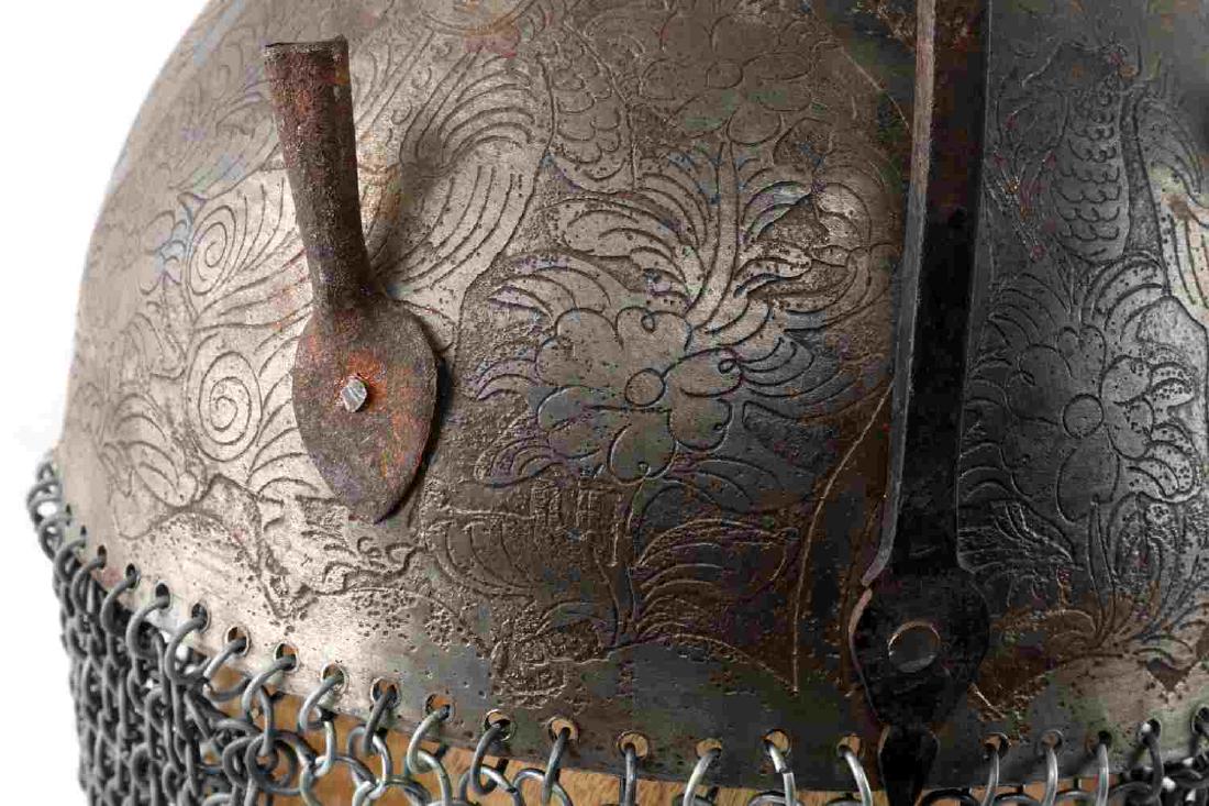 19TH CENTURY INDO PERSIAN STEEL KULAH KHUD HELMET: Indo-Persian “Kulah Khud”. Round steel skull engraved with circular floral panels and intricate designs. Two plume sockets affixed to front. Bottom accommodates a neck chain mail section. Swivel n