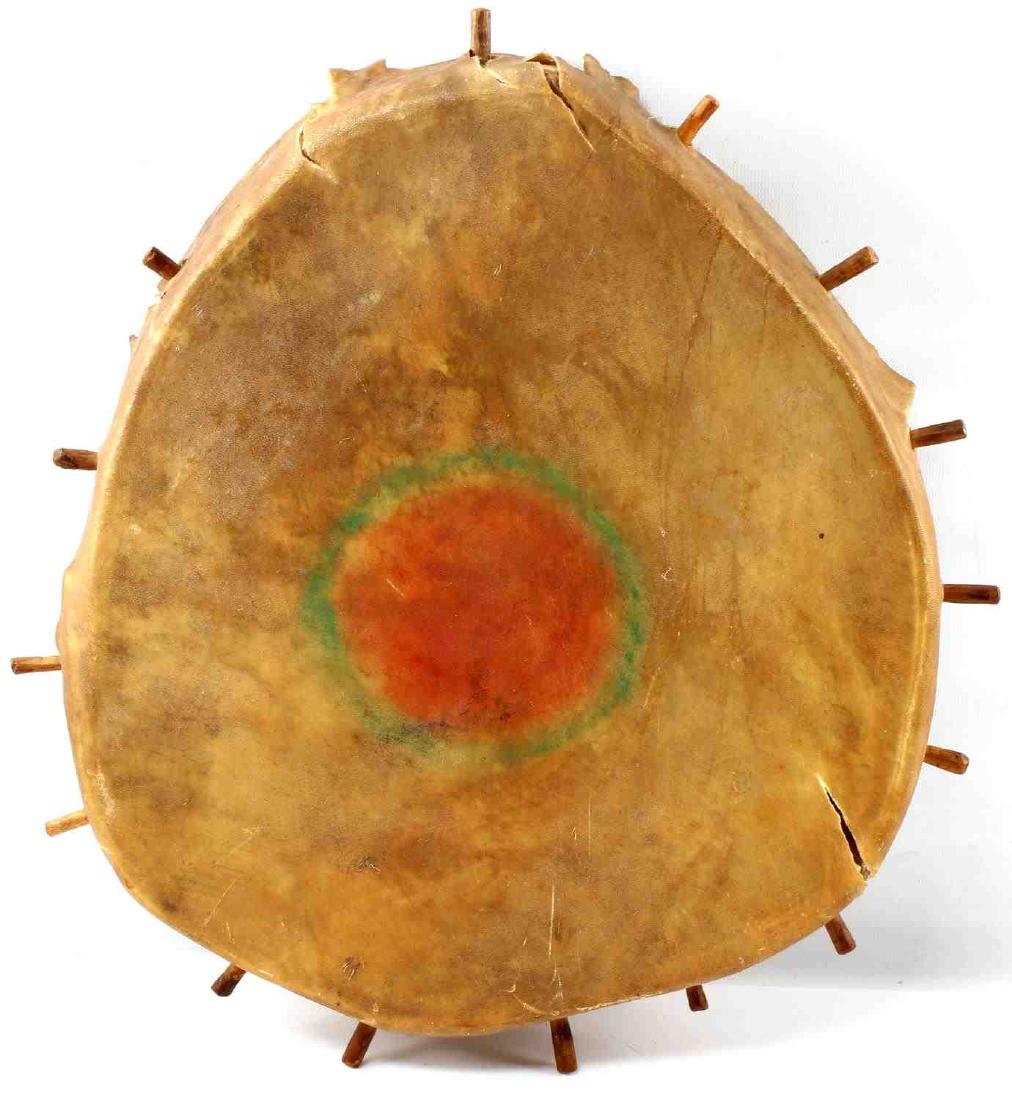 NATIVE AMERICAN RAWHIDE DRUM VINTAGE: Rawhide drum with wooden frame and spokes. Some colored dye to center. Large tear and smaller tear to face. Measures about 16 X 13 inches. Fair condition. From the collection of Duane R Campbell 1941-