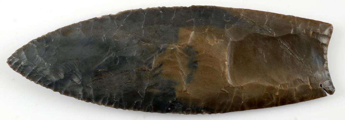 NATIVE AMERICAN MISSOURI PALEO ARROWHEAD: Paleo site arrowhead from dark gray stone. Found in Pike County, Missouri. Even flaking. Fluting on both sides. Upon magnification, there is an etched name and date. Bottom left corner broken and repa