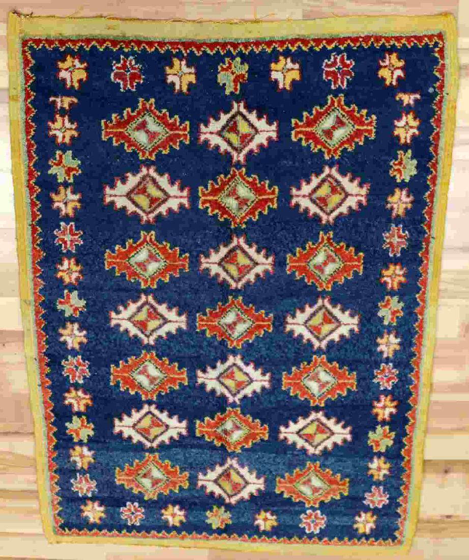 MULTI COLORED SMALL MOROCCAN RUG 3.5 BY 5 FEET: Moroccan rug with diamond pattern on the interior and star pattern on edges. Predominant colors of blue, orange, and white. Measures approximately 3.5 feet by 5 feet. In good condition.