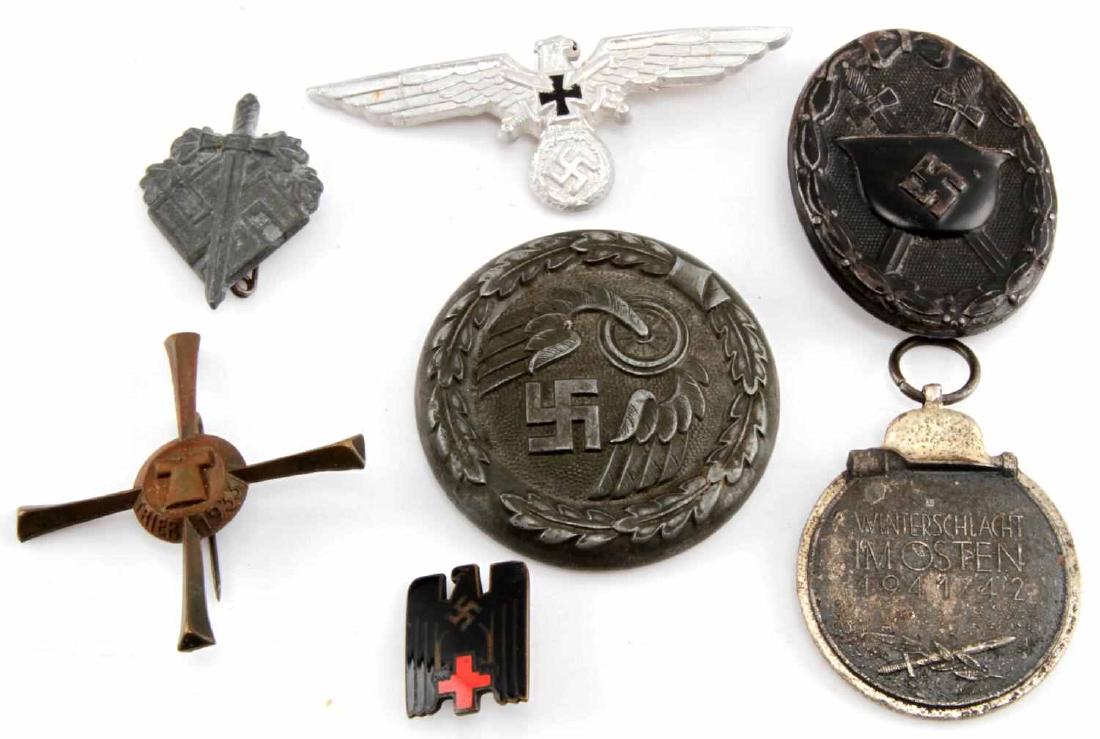 WWII GERMAN THIRD REICH BADGE AND PIN LOT OF 6: Lot contains six badges and pins from the Third Reich. Includes a Red Cross pin, black wound badge, Russian front medal sans ribbon, veterans hat badge, Trier 1933 pin, and a railroad officer's belt b