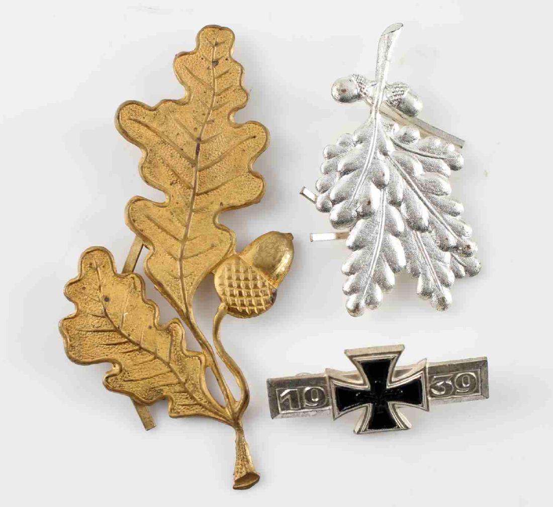 POST WWII GERMAN ARMY BADGE LOT OF THREE: Lot contains three badges if German origins which date from after WWII and denazification. Includes a silver and gold colored oak leaf clusters and a small Iron Cross pin. All are in very good conditi