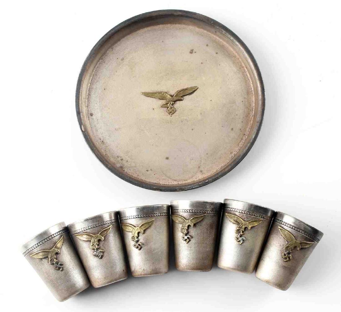 WWII GERMAN LUFTWAFFE PILOT SCHNAPPS CUP LOT OF 7: German Luftwaffe pilot's schnapps cups with tray. Each piece has affixed Luftwaffe Reichsadler at their fronts. Good condition overall. Some discoloration and signs of abrasions present. 7 pieces in t