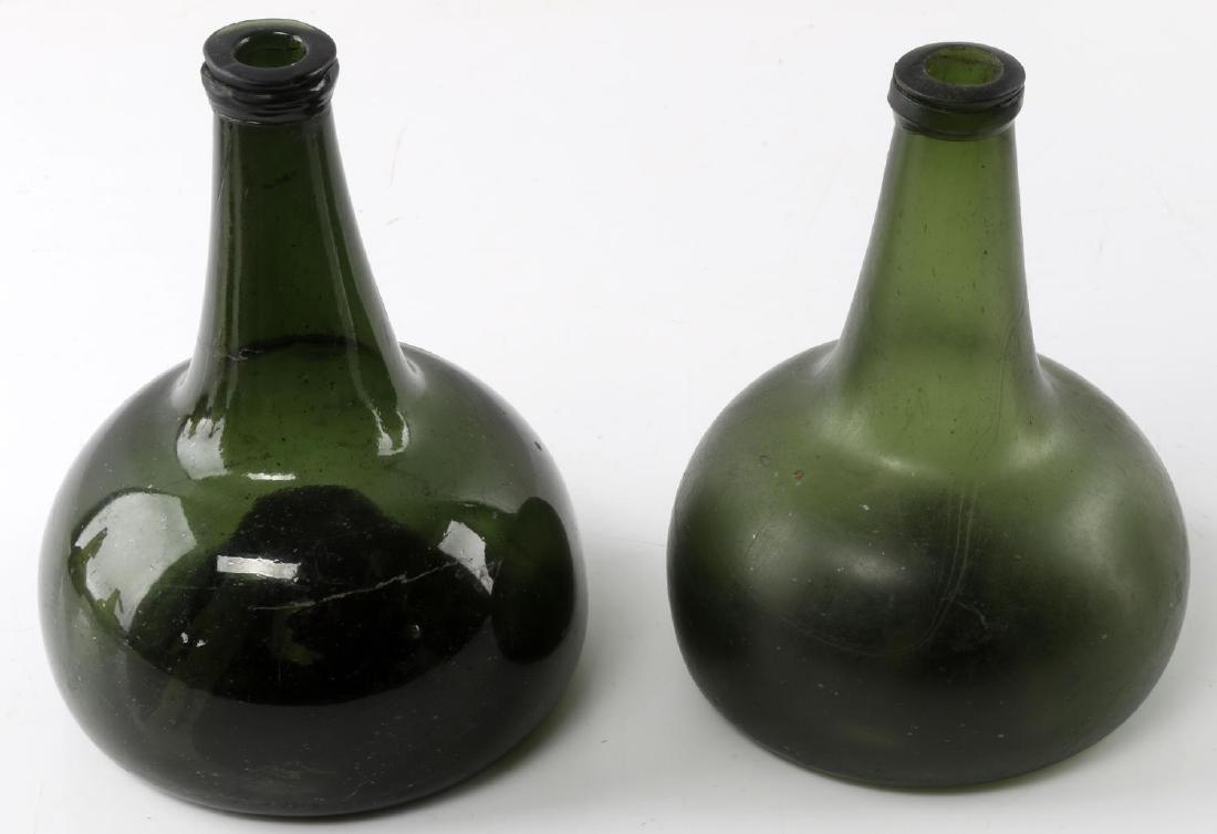 TWO ONION SKIN GREEN MALLET OPEN PONTIL BOTTLES: One measures 7.5 inches tall with a darker tone glass. Lighter green tone glass measures 7 inches. Both are in good condition. Some scratches present but no cracks.