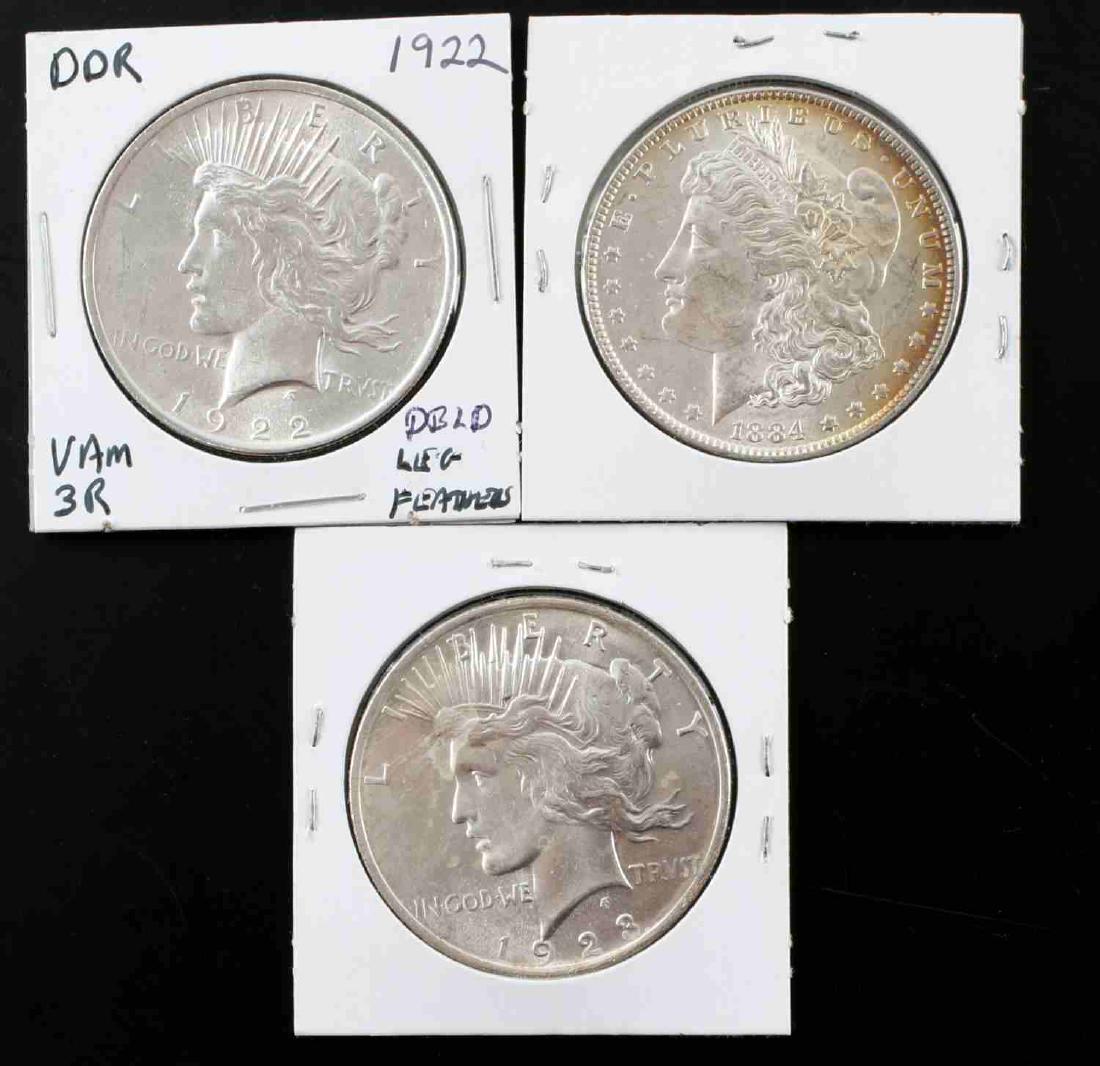 MORGAN PEACE SILVER DOLLAR LOT 3 BETTER & VARIETY: Included are 3 silver dollars. One Morgan 1884-) with attractive rainbow toning over 2/3 of the reverse in Choice Mint State. Also 2 Peace Dollars with reverse doubling: 1922 with doubled leg feather 