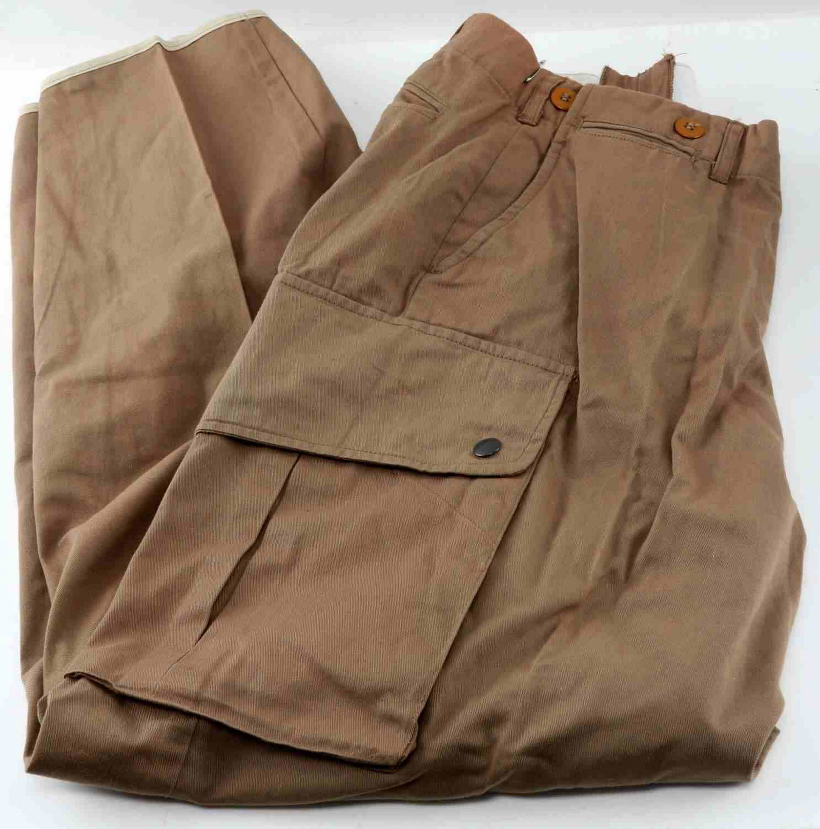WWII US AIRBORNE M 42 PARATROOPER JUMP PANTS: WWII U.S Army Airborne Paratrooper's jump pants in khaki. Interior of waistband is marked with "INSEAM 34", WAIST 36". Pants are complete with side and cargo pockets with original metal snaps & rivets
