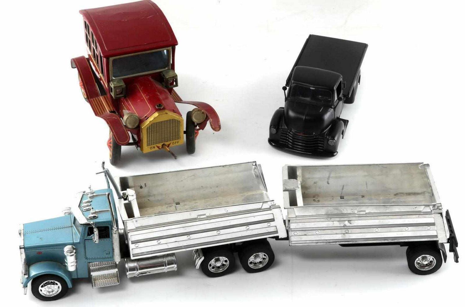 LOT OF THREE TOY TRUCKS & CARS VINTAGE TIN TOURING: One red vintage tin touring car. Battery operated with intact headlights. Measures 9.25 inches by 4.5 inches by 5.5 inches. Some areas of rust but in good condition. One matte black Jada Toys flatbed 