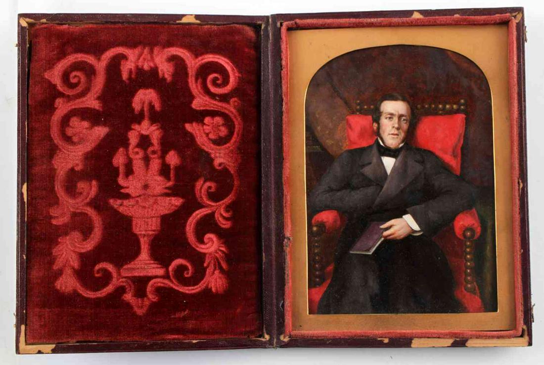 SEATED PORTRAIT MINIATURE IN TOOLED LEATHER CASE: 19th century oil portrait of gentleman seated in a plush velvet chair with book on his lap. Pre-dates the 1850s. In a tooled leather case with red velvet interior. Painting is in very good condition. 