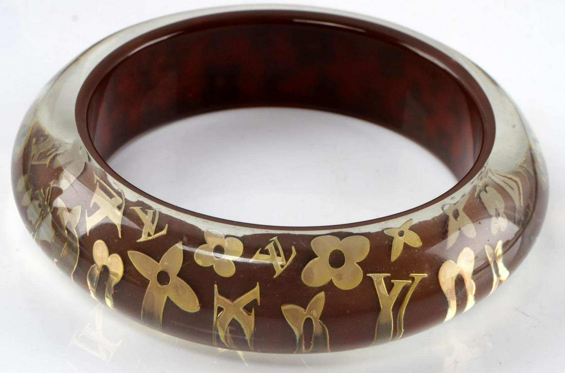 LOUIS VUITTON MONOGRAM INCLUSION BRACELET: Louis Vuitton monogram inclusion lucite bracelet. Gold monograms and fleurs inside of the lucite bracelet. Measures 7.5 inches. In good condition.