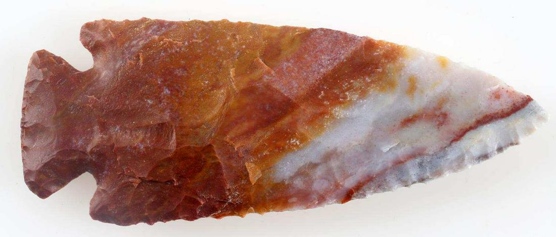 GRAND STYLE ARROWHEAD POINT MULTI COLOR CHERT: Orange-red to lighter gray blue chert, broad flaking with little secondary chipping, wide convex base, corner notched, measures 4.5 inches long. Very good condition.