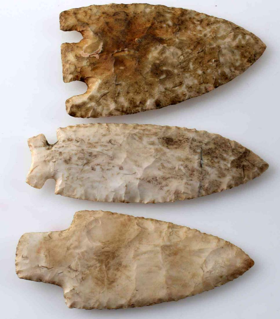 LOT OF 3 EARLY & MIDDLE ARCHAIC STYLE ARROWHEADS: Hidden Valley style of creamy white lithic, rounded base, broad random flaking, edges sharp to touch. Measures 4.75 inches. In good condition. Smith style of mottled lithic, broad with random flaking,