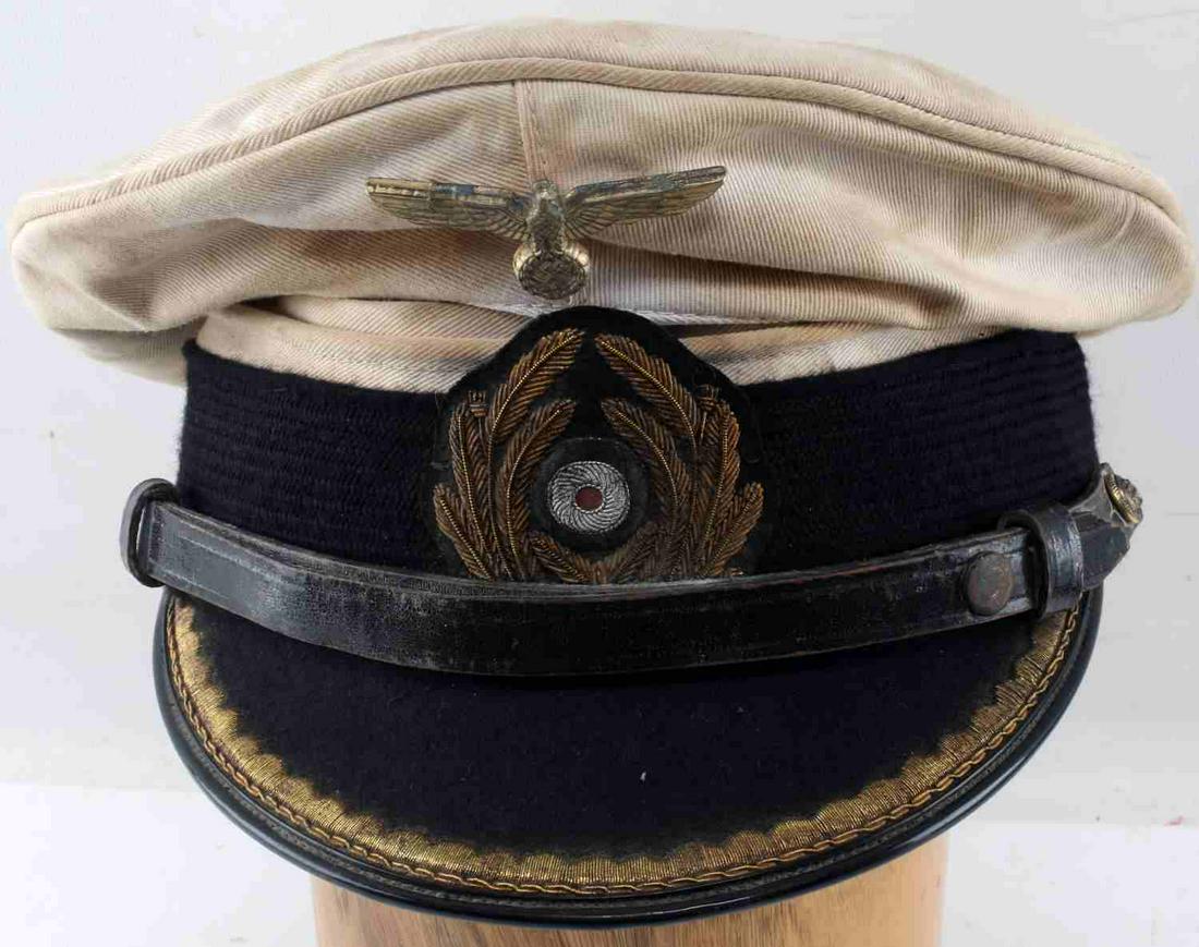 WWII GERMAN THIRD REICH KRIEGSMARINE VISOR CAP: German summer pattern Kriegsmarine Junior Officer visor cap. White cloth construction with gold bullion wire scrambled eggs and oak leaves and silver bullion cockade. Interior maker marked "EREL Berli