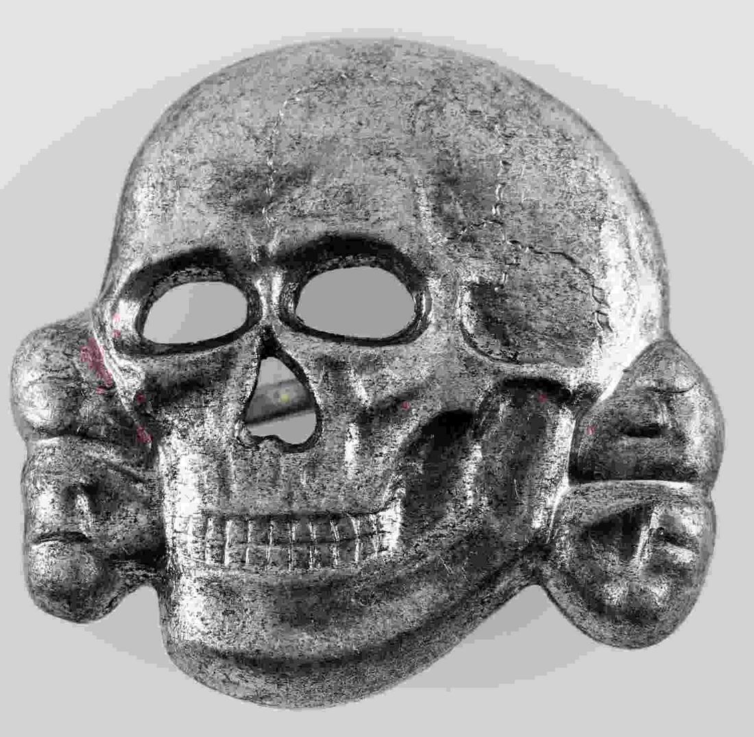 WWII GERMAN SS TOTENKOPF VISOR CAP BADGE: German totenkopf visor cap badge. Reverse side is maker marked "RZM M1/24." Has two flat horizontal prongs on the back side that are crimped into place. Stamped nickel construction. Unauthenticated; s