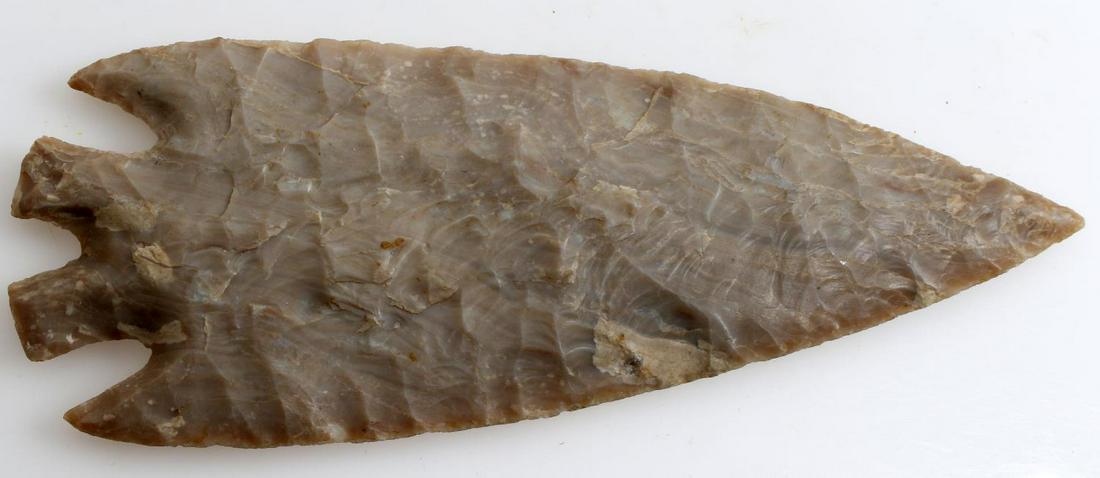 LIGHT GREY SPLIT BASE ARROWHEAD POINT LOUISIANA: Light grey with underlying striations, broad and parallel flaking, split base, corner notched point, measures 6.5 inches long. From Central Louisiana collection, believed Texas Provenance._
