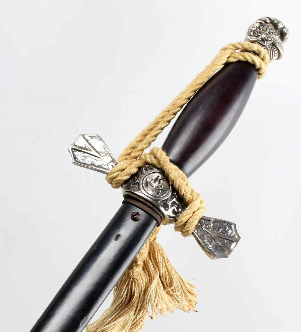 KKK KU KLUX KLAN LADIES SWORD WITH KNOT: KKK Ladies sword. The letters KKK are on the backside of the cross guard. Double edged sword with a visored knight's head on the end of the grip. There are chips on the scabbard paint and dark spots o