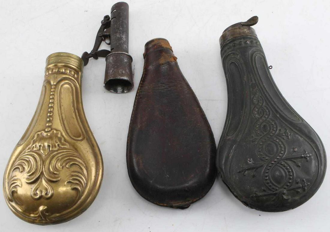 VINTAGE BLACK POWDER FLASK LOT OF THREE: Vintage black powder flask lot of three. One leather flask stamped "warranted solid" comes with the spout, two flasks made of brass. The brass flasks have bohemian designs. Flasks are in good to very 