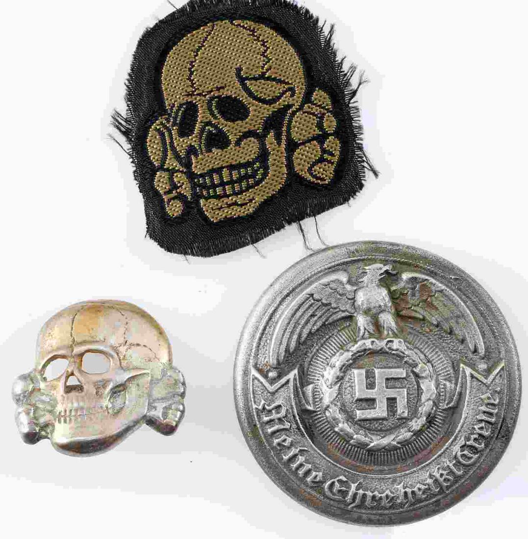 WWII GERMAN THIRD REICH MEDAL LOT OF THREE: WWII German medal lot of three. The lot includes an M1/52 Deschler SS totenkopf medal, a cloth totenkopfs and an SS officer buckle rondel. The buckle rondel is missing the pin in the rear. The Deschle