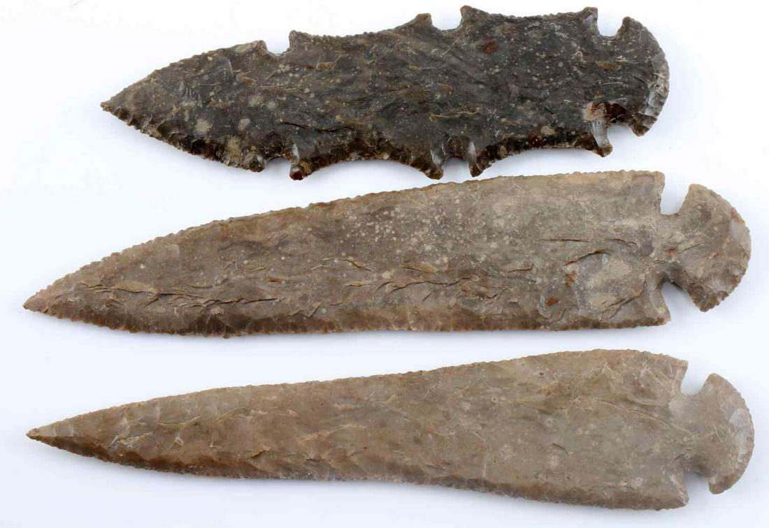 LOT OF THREE MID TO LATE ARCHAIC ARROWHEADS: Three very finely carved arrowheads. One dovetail of dark brown lithic with broad flaking. One waisted dovetail of dark brown lithic with broad to narrow flaking. One eccentric of dark gray with nice