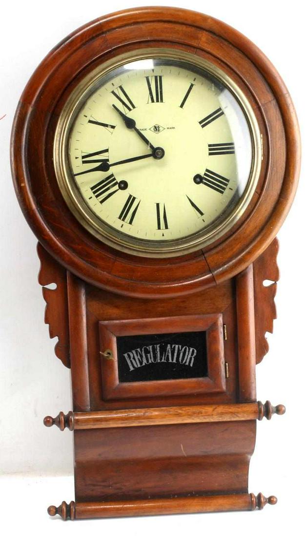 VINTAGE WOODEN WALL CLOCK CM TRADEMARK: Hanging wall clock with roman numerals and hour and minute hands. CM inside diamond trade mark marked to front. Regulator marked to window where movement is. Label at top reads 'C.M.A. Examiners By Th